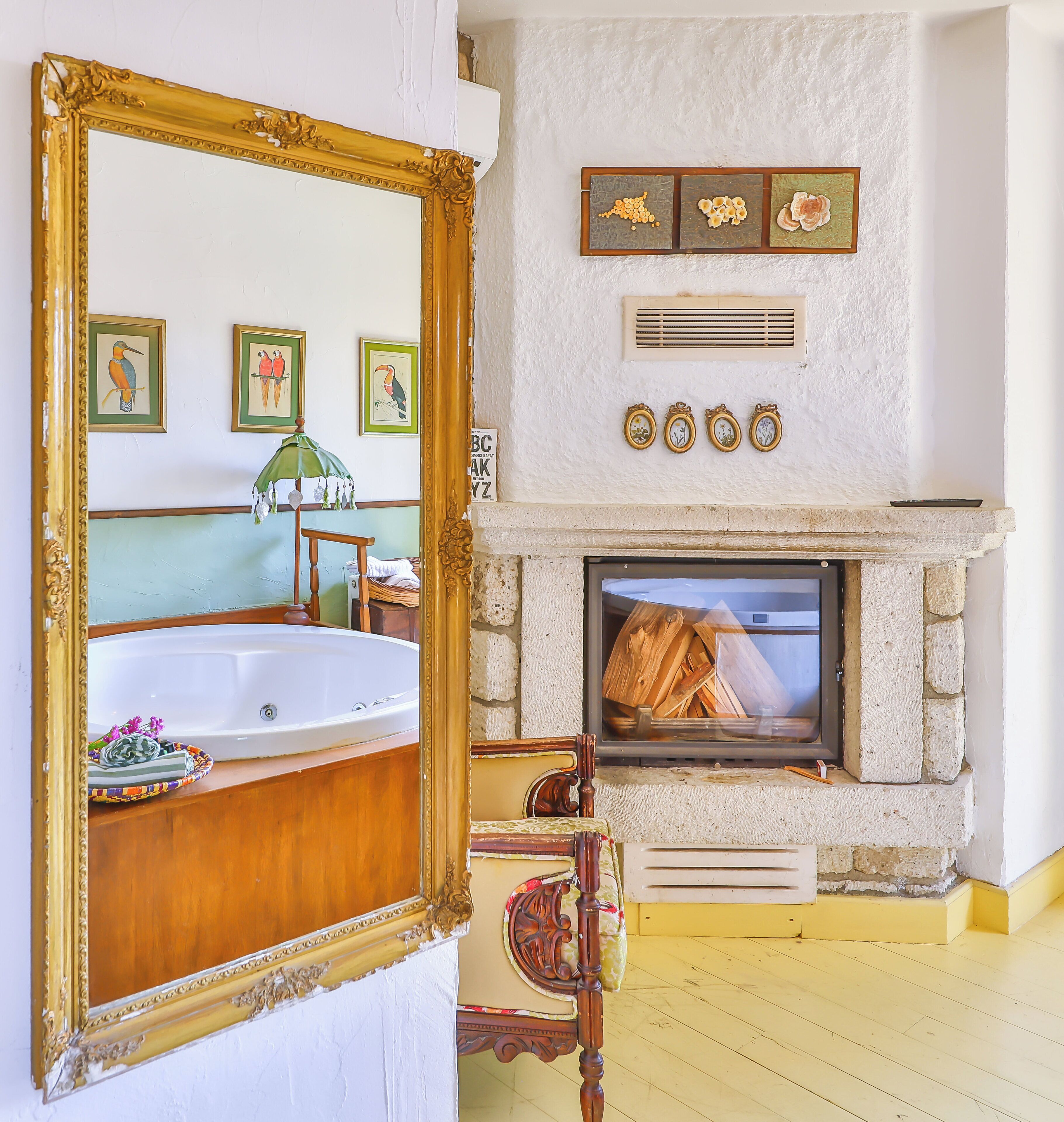 A bathroom with a large mirror, a bathtub, and a wooden chair.