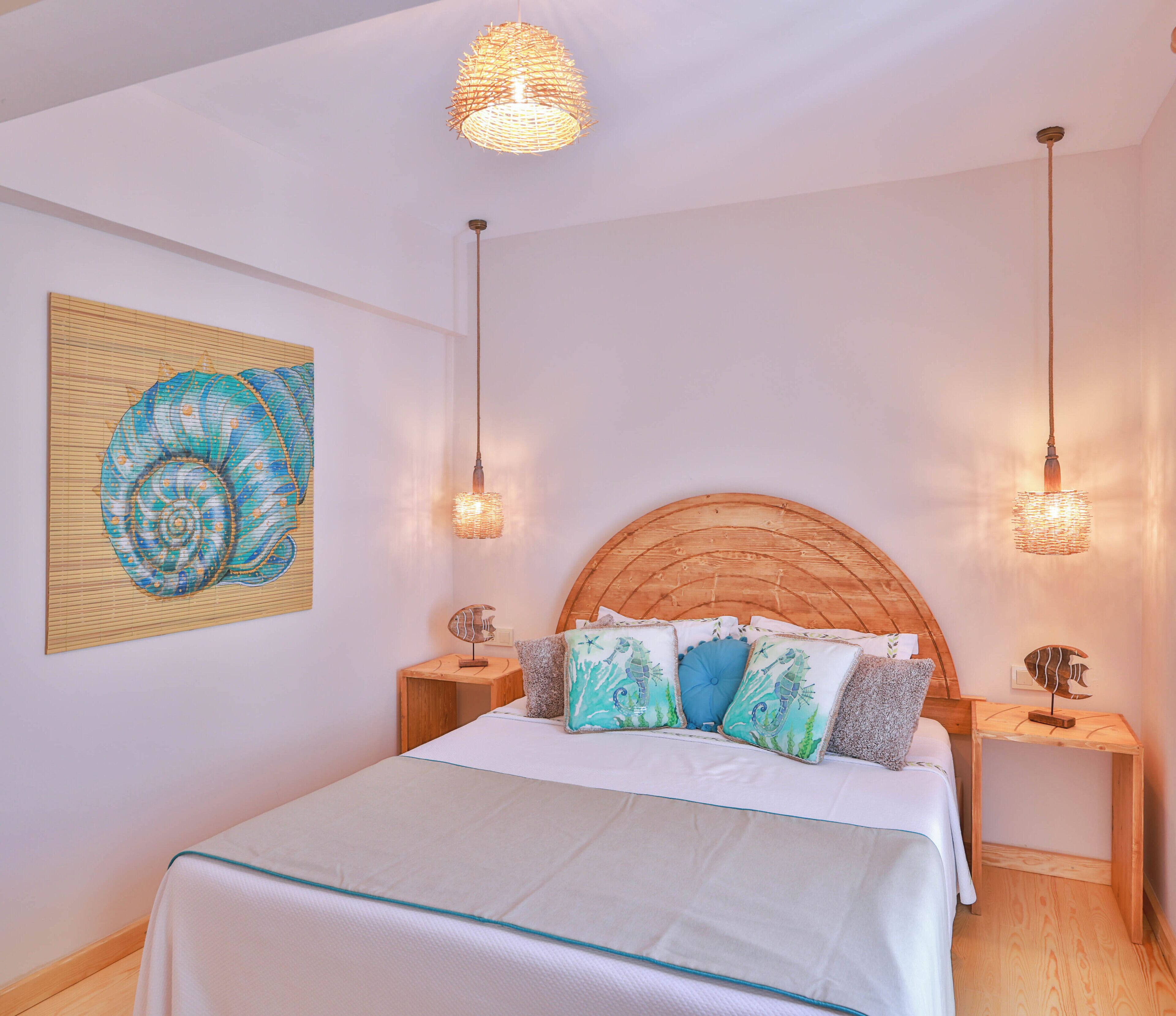 Ein Schlafzimmer mit hölzernem Kopfteil, einem Bett mit weißer Bettwäsche, zwei Nachttischen mit Lampen und einem Wandbild.