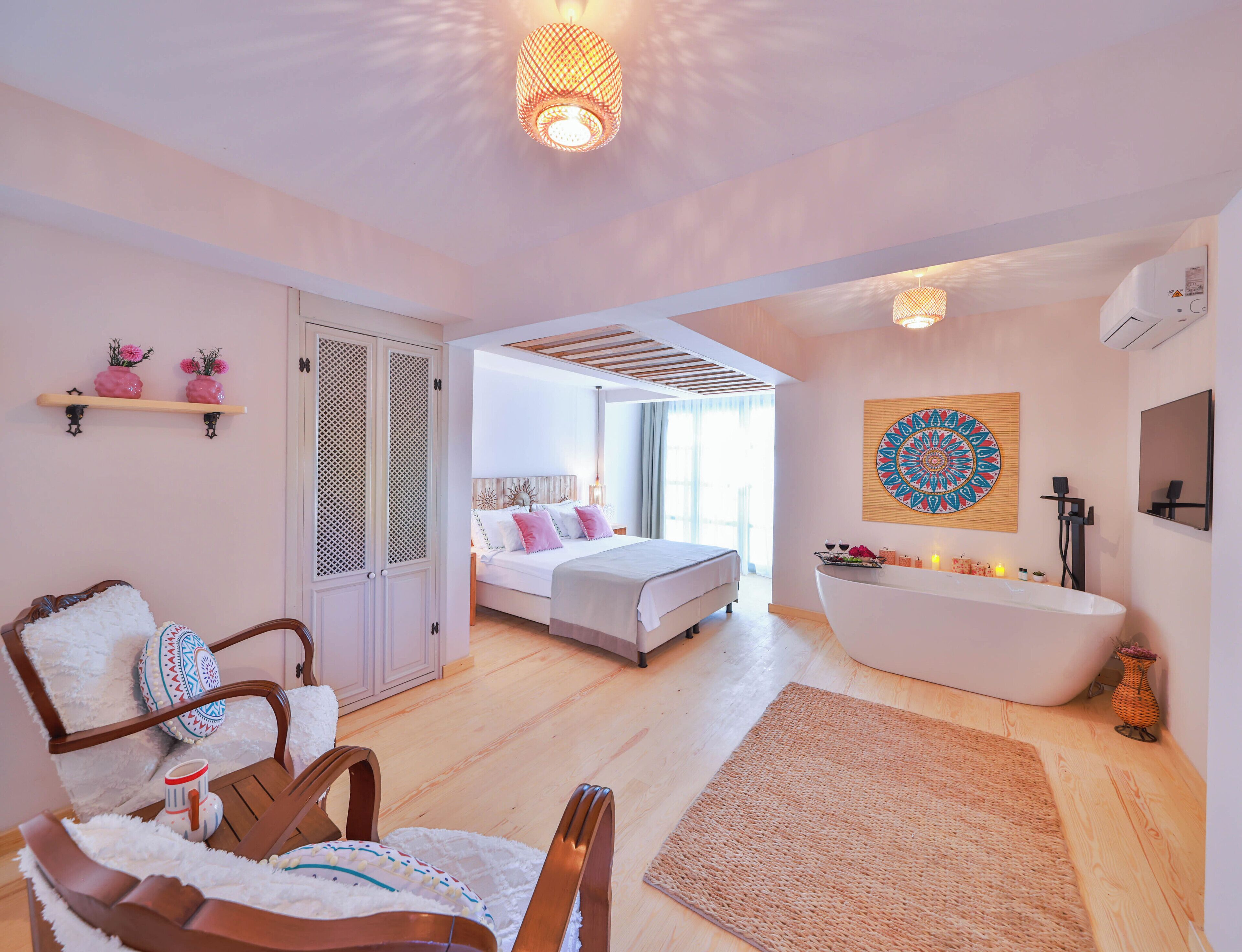 A hotel room with a bed, a sitting area with a chair, a bathtub, and a wall-mounted artwork.