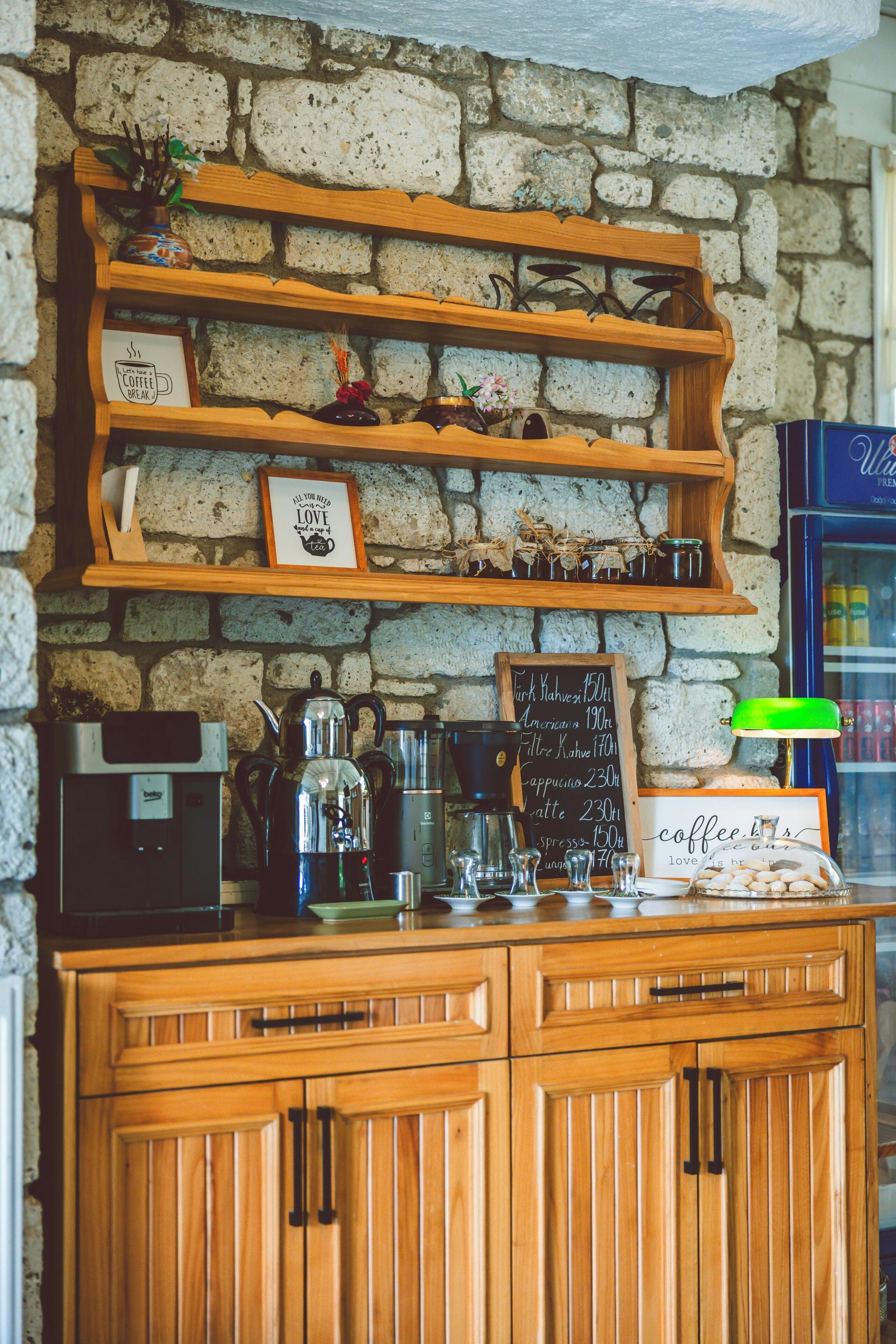 A coffee shop with a stone wall, wooden shelves, a coffee machine, and a chalkboard menu.