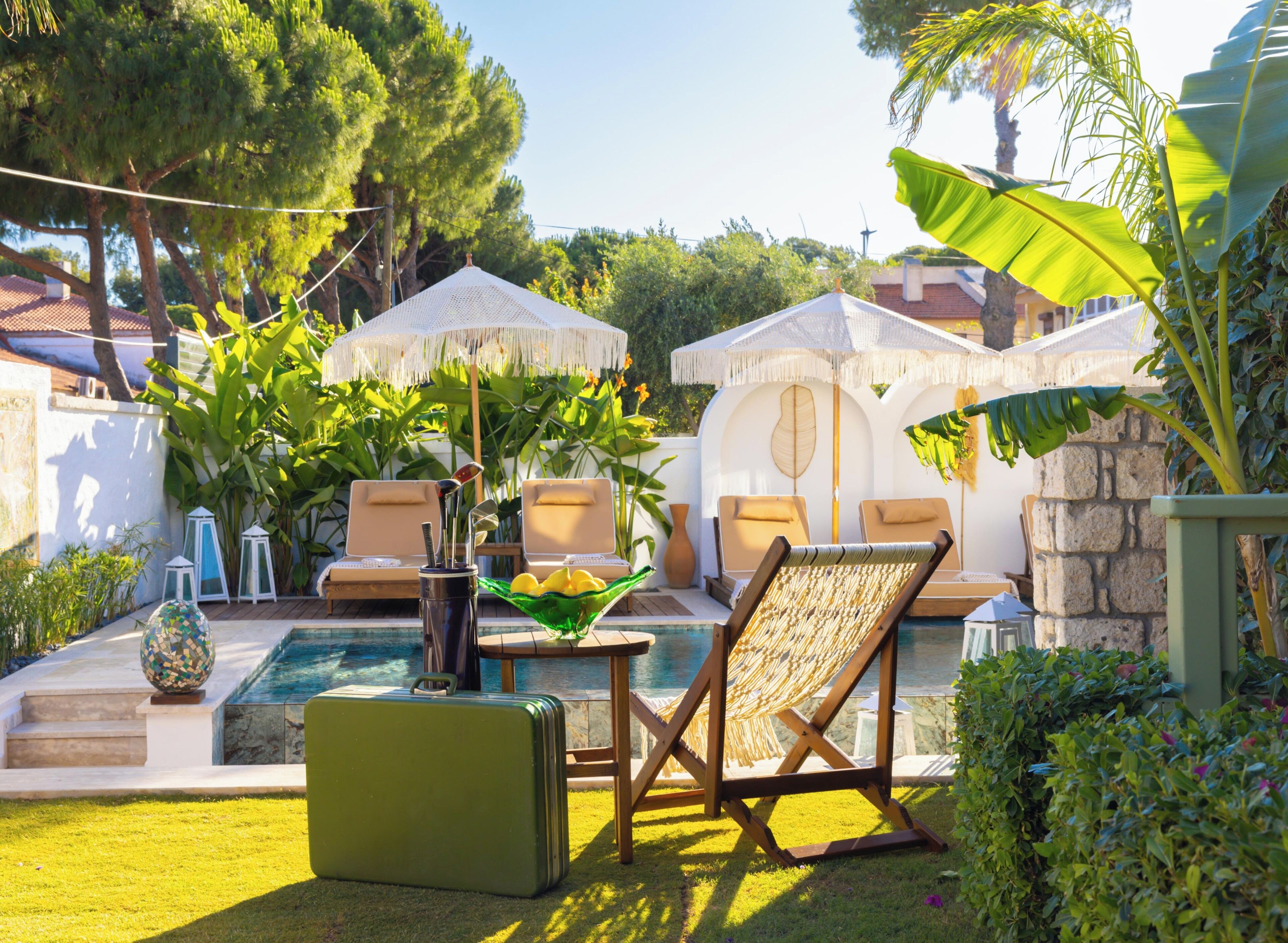 A poolside area with lounge chairs, a table with a bowl of lemons, and a suitcase.