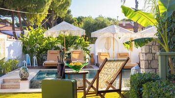 A poolside area with lounge chairs, a table with a bowl of lemons, and a suitcase.