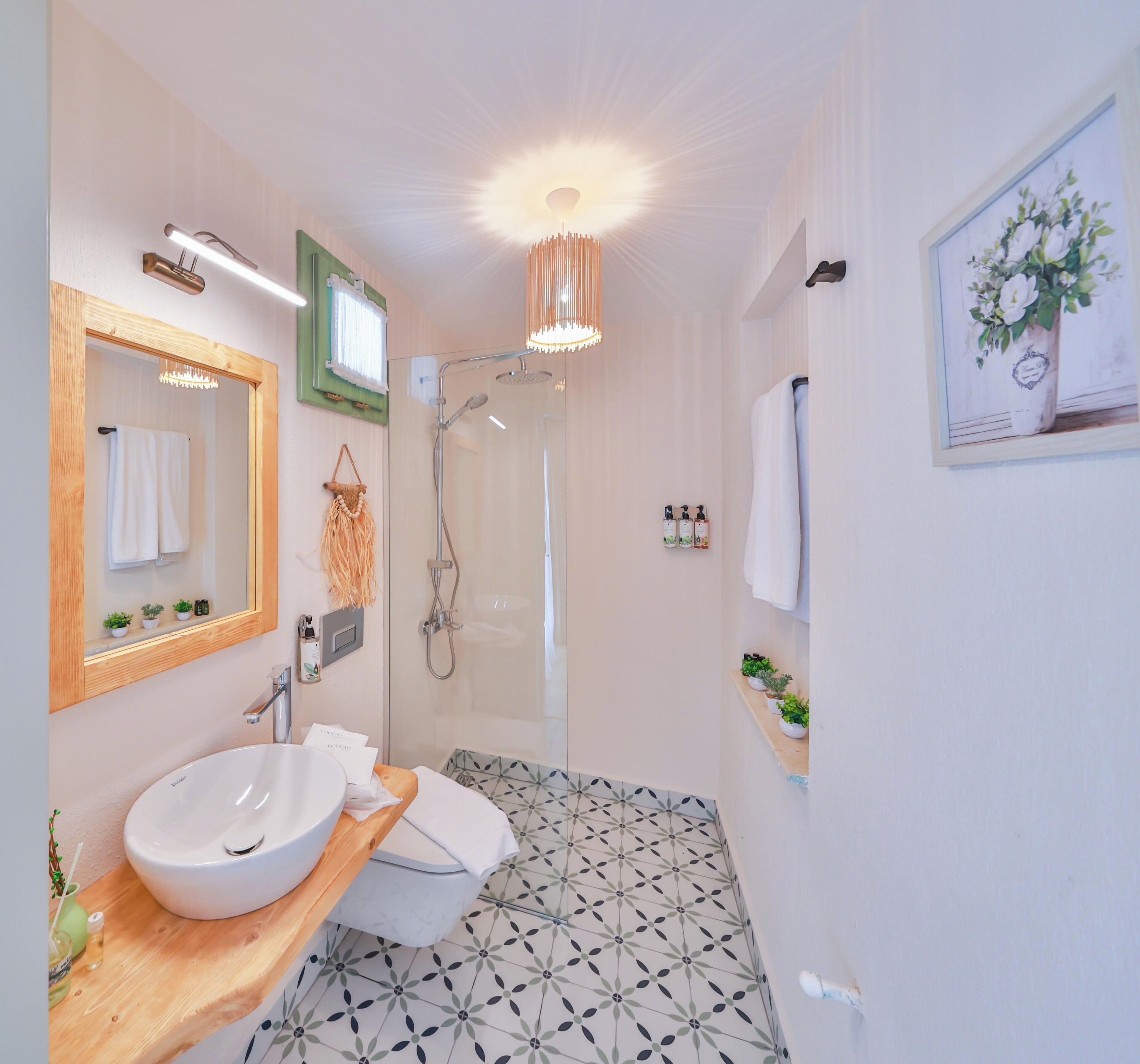 A modern bathroom with a large sink, a shower, and a mirror.