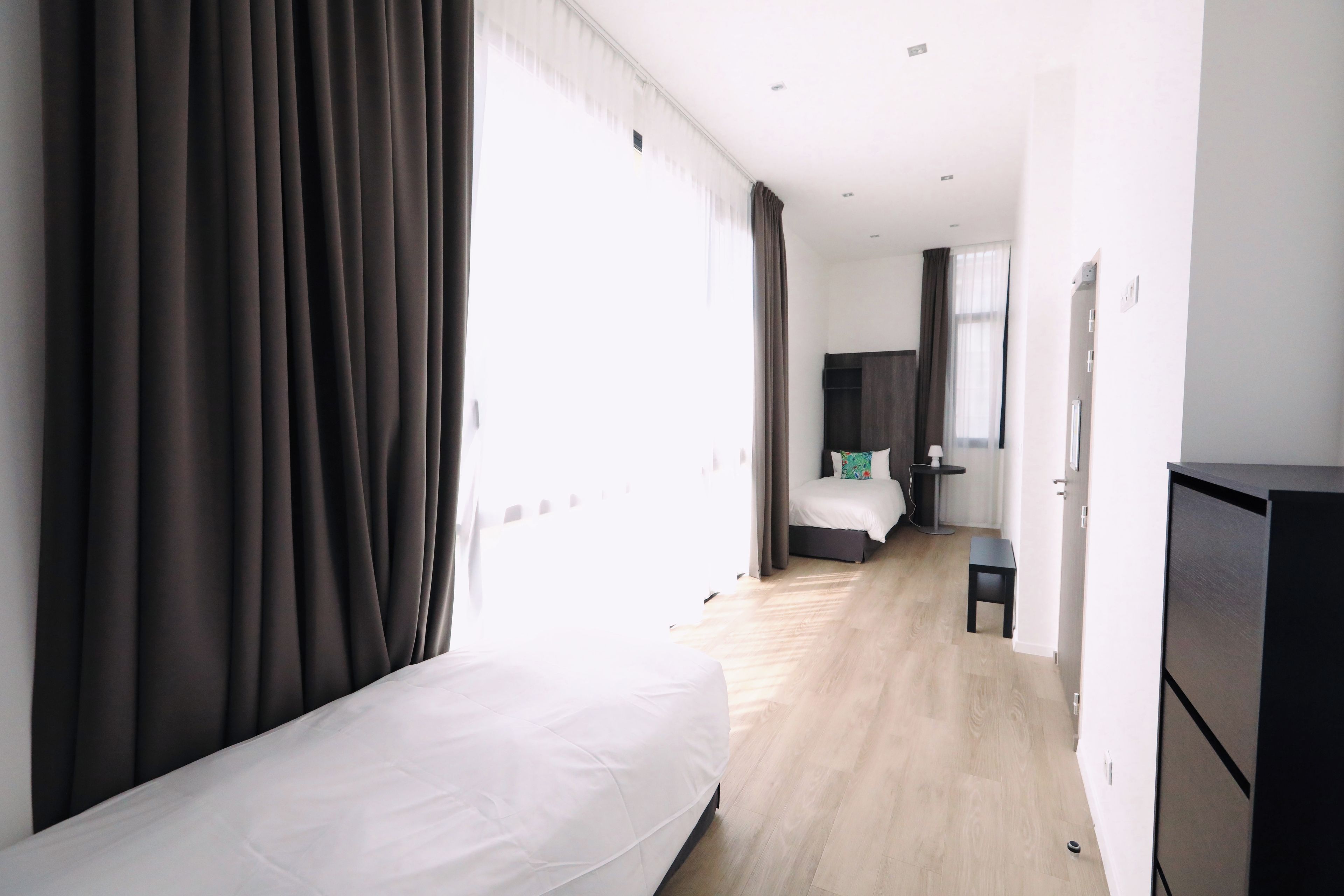 Quarto de hotel com cama, escrivaninha e guarda-roupa.