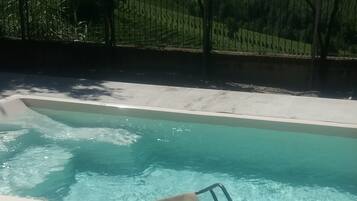 Una piscina al aire libre de temporada, sillones reclinables de piscina