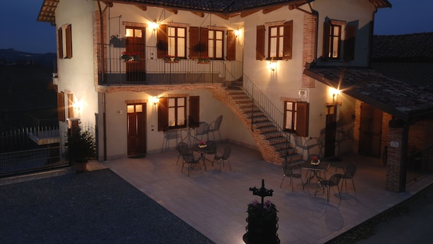 Una casa de dos pisos con balcón, zona de estar exterior y una escalera.