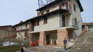 Una casa de dos pisos con un balcón, un tobogán rojo y una piscina pequeña.