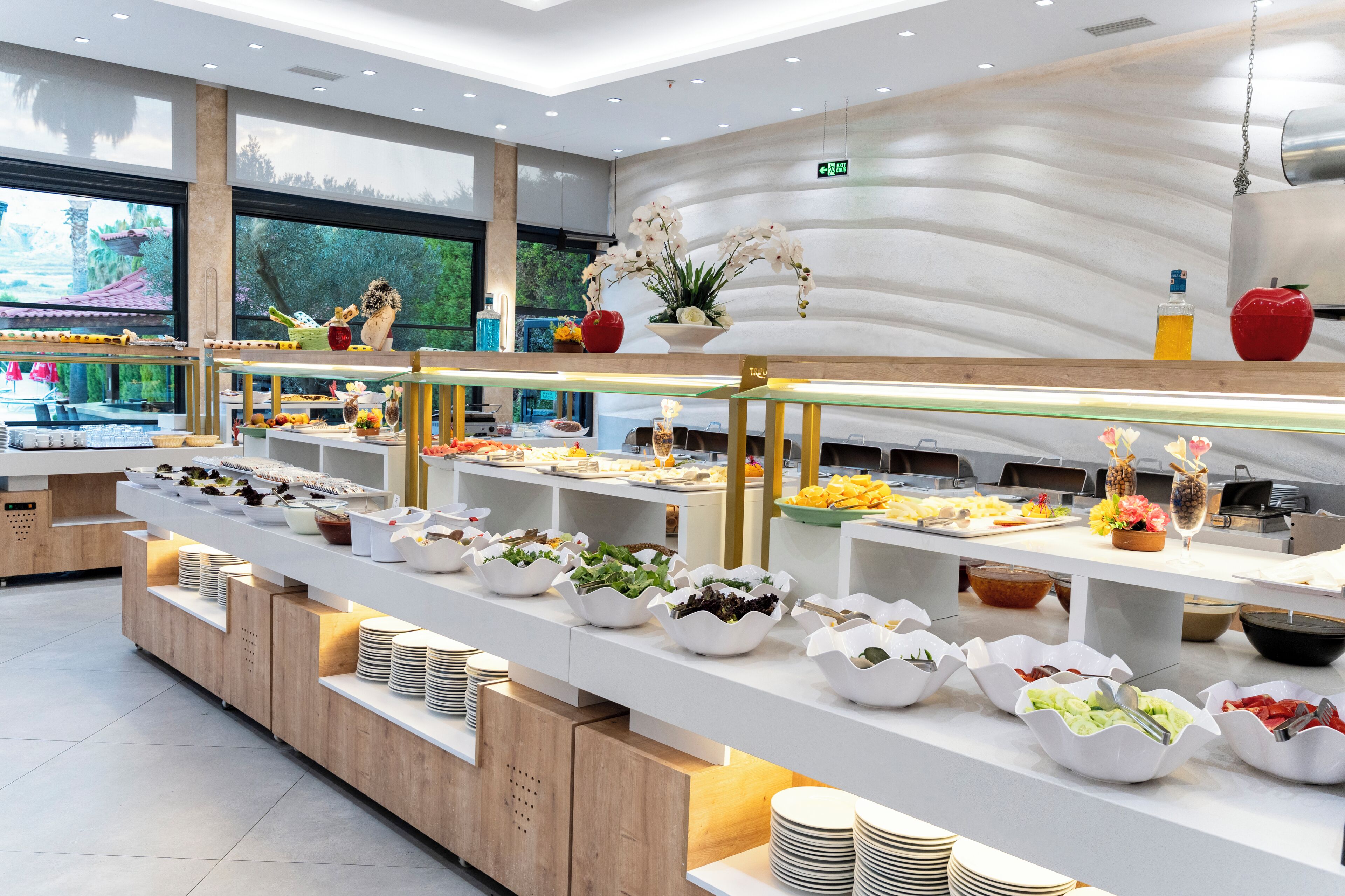 A buffet setup with multiple food stations, a variety of dishes, and a decorative plant arrangement.