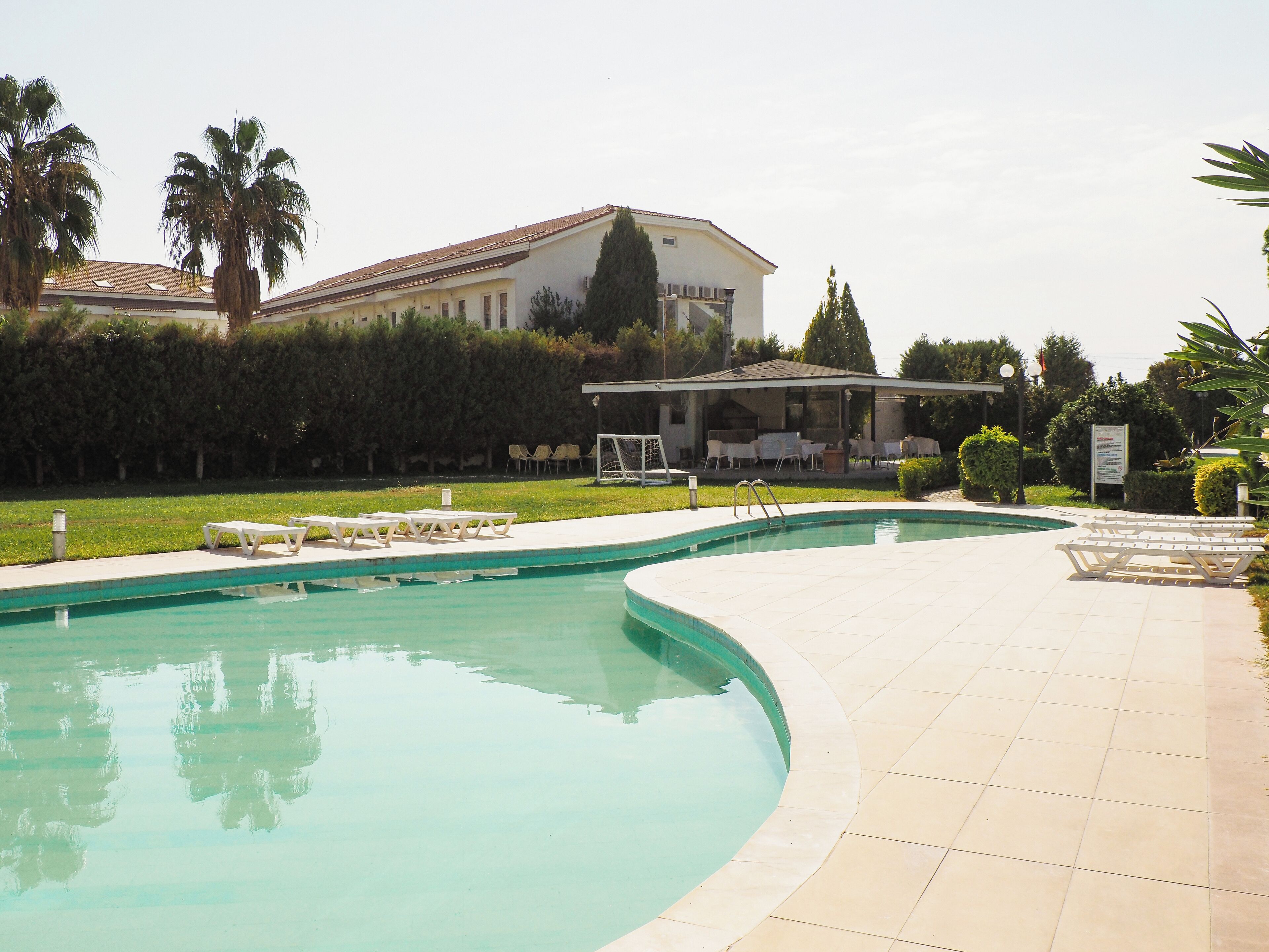 A swimming pool with lounge chairs and a covered seating area.