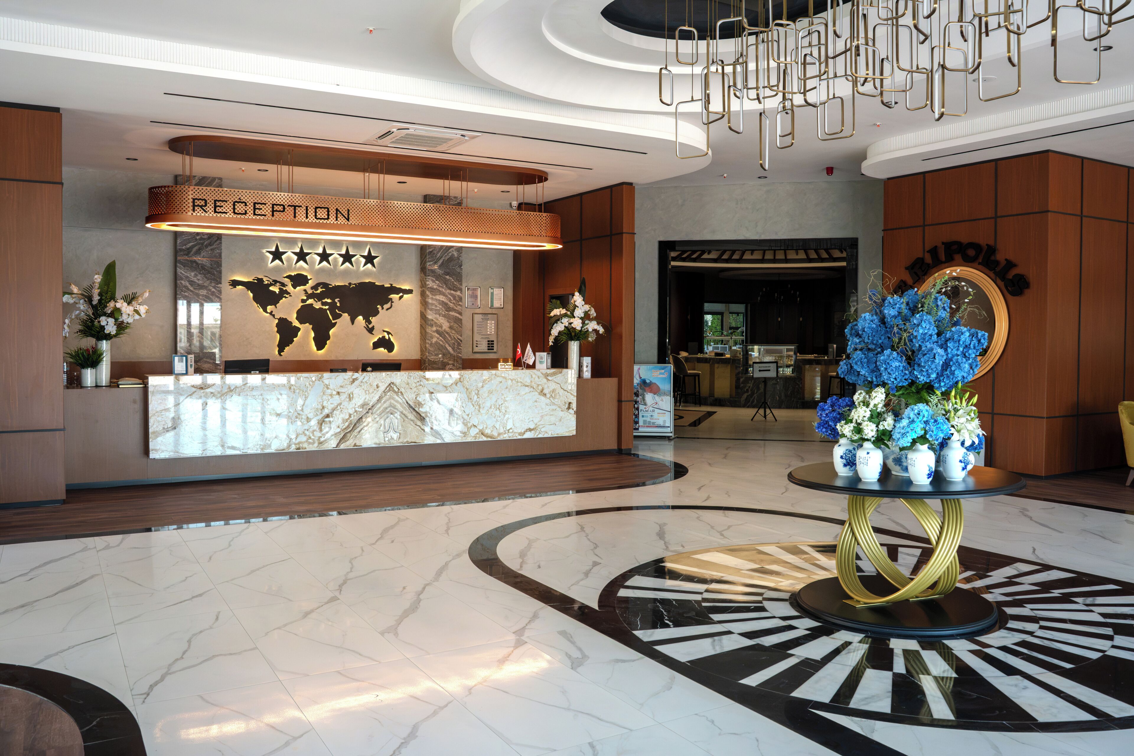 Zona de recepción de un hotel, con piso de mármol, un mostrador de recepción, un mapa mundial y el letrero de recepción.