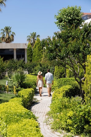 A pathway flanked by lush greenery and a building with a modern design. - Tripolis Hotel (Denizli)