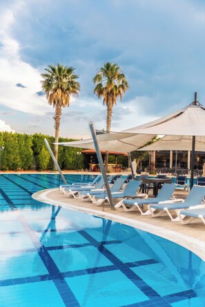 A swimming pool with lounge chairs and palm trees. - Tripolis Hotel (Denizli)
