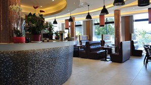 A modern hotel lobby with a curved reception desk, seating area, and large windows. - Hôtel de la seine (Epinay-sur-Seine)