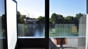 A balcony with a view of a bridge, trees, and a body of water. - Hôtel de la seine (Epinay-sur-Seine)