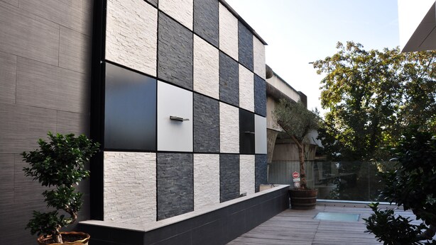 A modern building with a checkered facade, a wooden deck, and potted plants. - Hôtel de la seine (Epinay-sur-Seine)