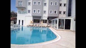 A swimming pool with lounge chairs, a building labeled "The Park Marmaris" with multiple windows, and a covered area with glass doors. - The Park Marmaris Hotel (Marmaris)