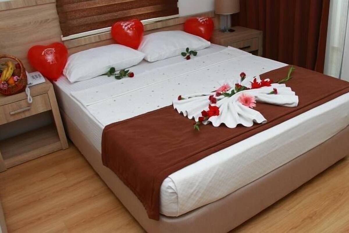 A neatly made bed with a brown blanket, white pillows, and a floral arrangement on the bedspread.