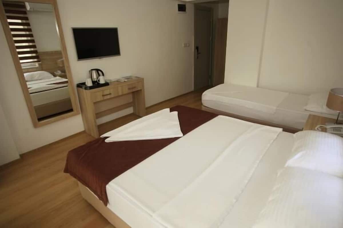 A hotel room with a bed, a desk, a chair, a TV, and a bathroom door.