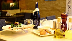 A dining table with a bottle of wine, a plate of food, and condiments. - The Park Marmaris Hotel (Marmaris)