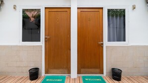 Puerta de madera doble con los números 7 y 8, un felpudo y un basurero al frente.