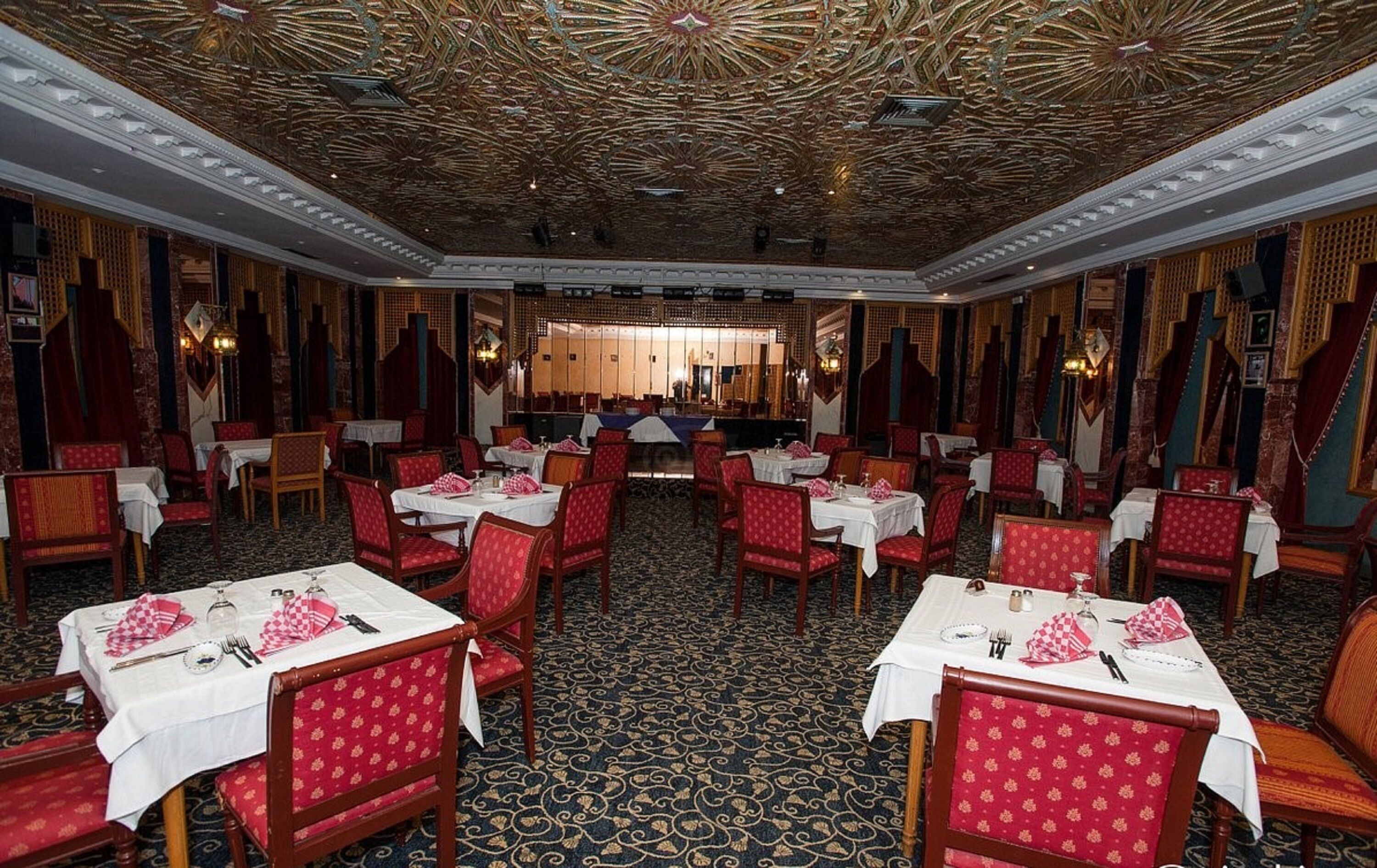 Un salón de banquetes con mesas dispuestas para comer, techo ornamentado y decoración tradicional.