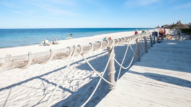 A beach with a wooden boardwalk, beach chairs, and umbrellas. - Hotel Riviera - Family Only (Port El Kantaoui)