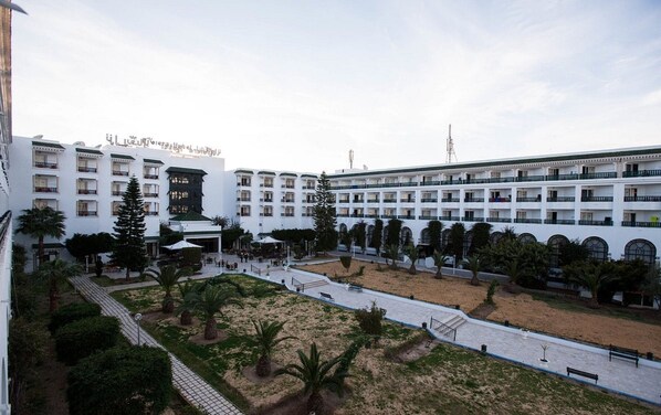 A hotel with multiple floors, outdoor seating areas, and a central courtyard with palm trees.