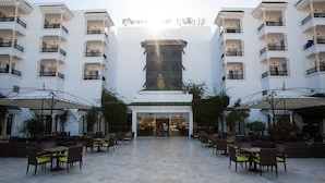 A hotel with a central tower, outdoor seating area, and multiple balconies. - Hotel Riviera - Family Only (Port El Kantaoui)