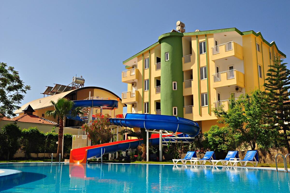 Um hotel com piscina, toboáguas e um edifício verde e amarelo.