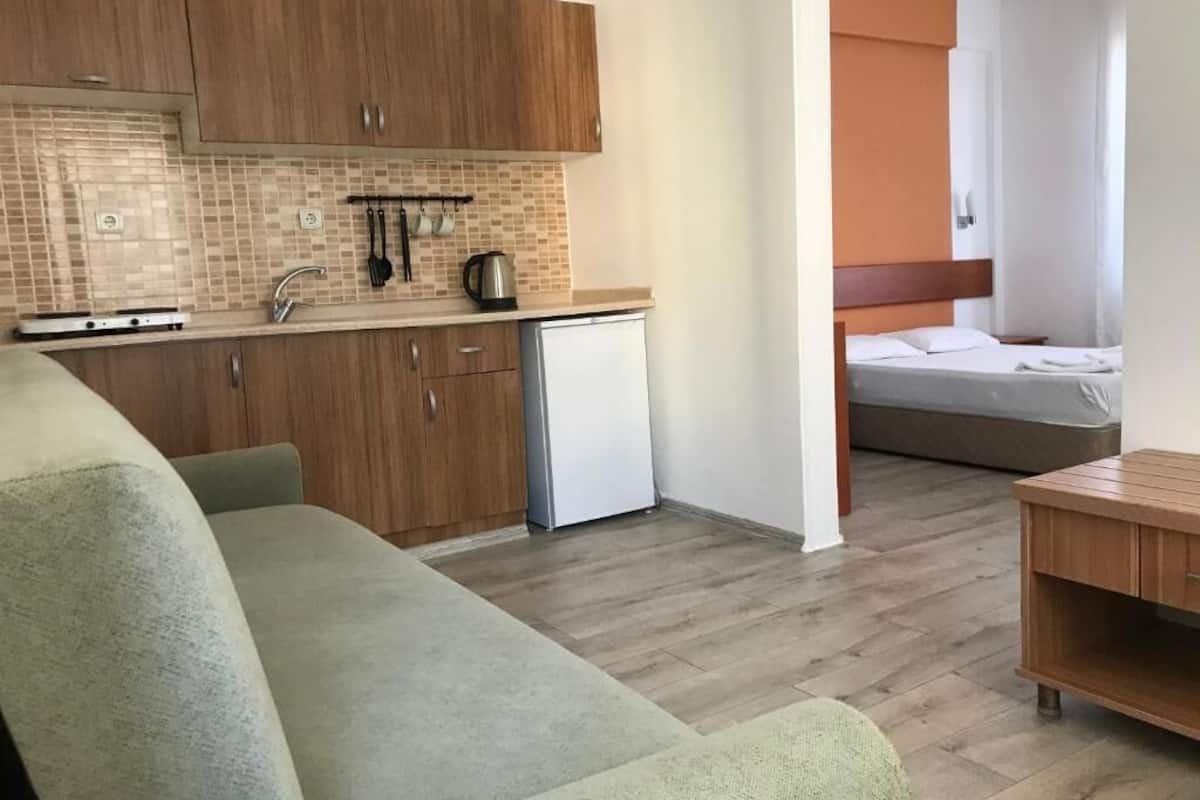 Um espaço compacto com cozinha compacta, um sofá, uma cama e uma pequena mesa de madeira.