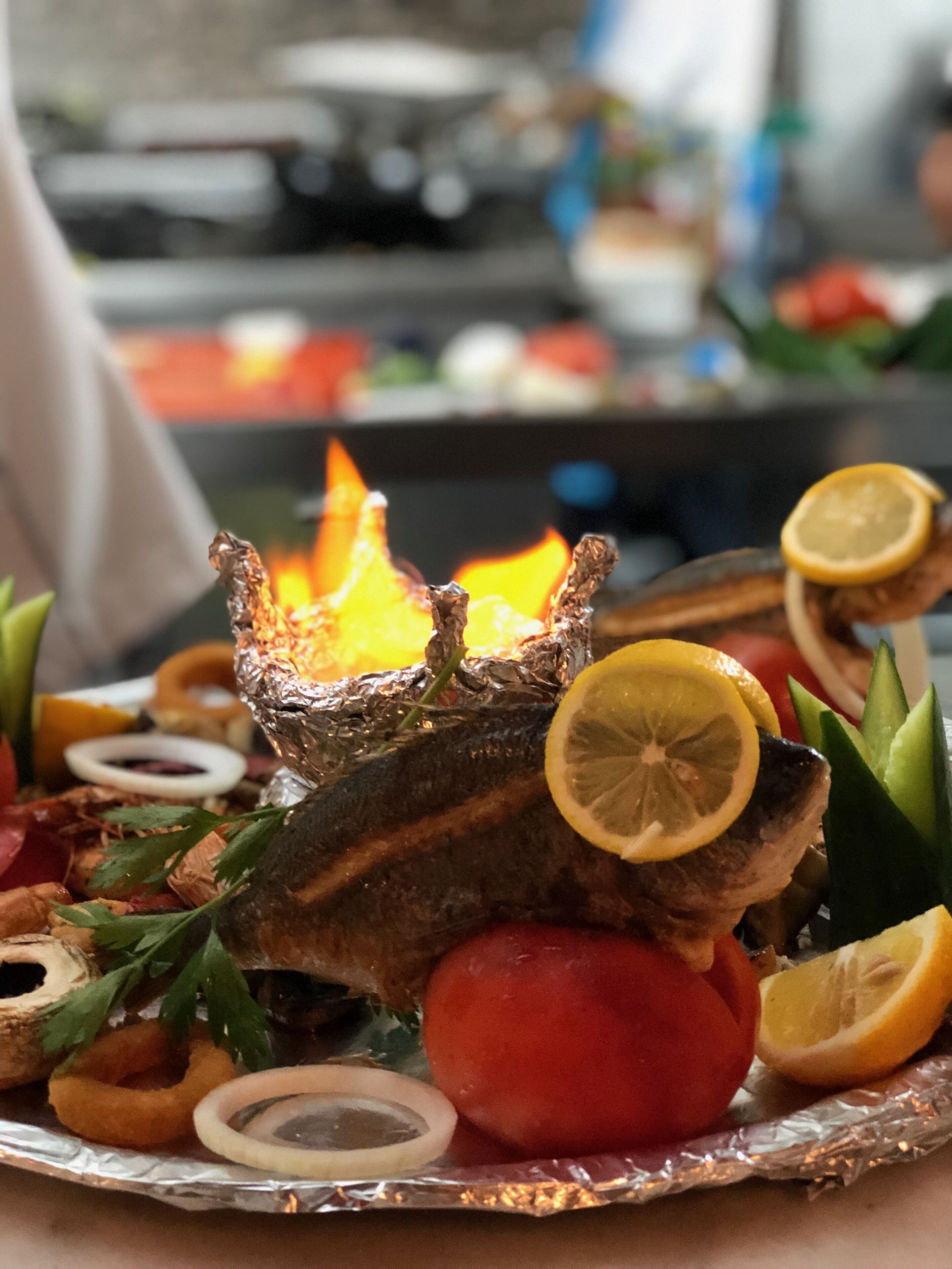 Pescado asado con rodajas de limón y guarniciones sobre una bandeja.