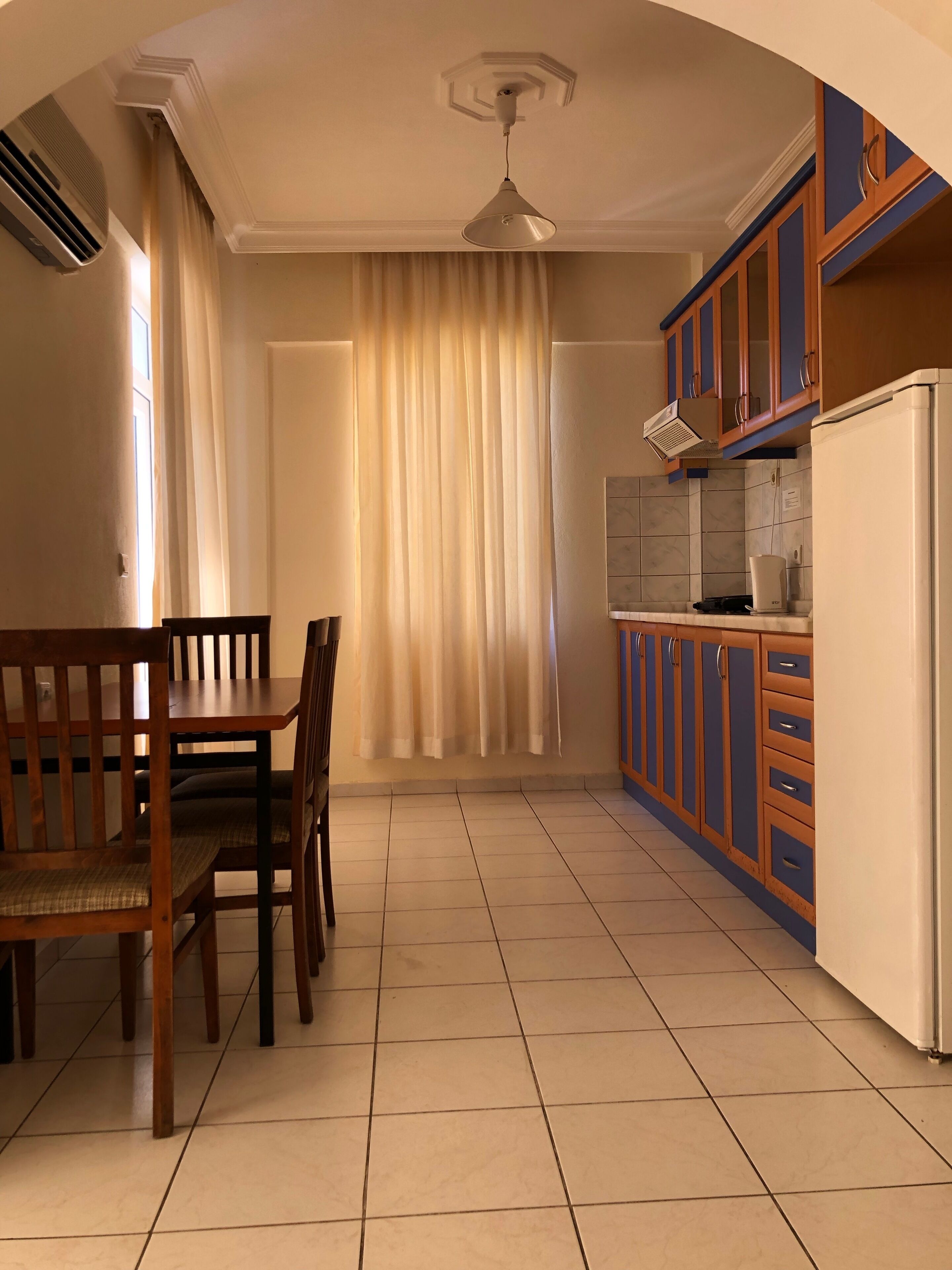 A kitchen with a dining table and chairs, a refrigerator, and cabinets.