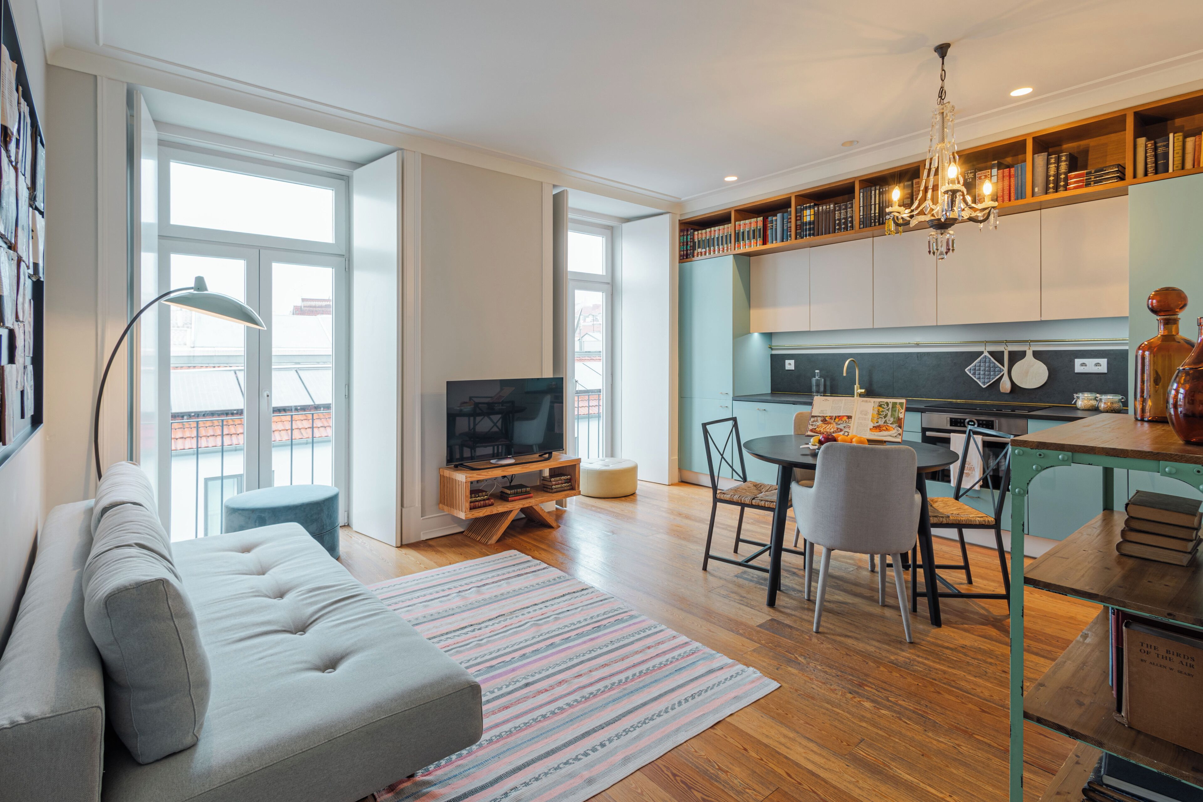 Una sala de estar moderna con sofá, televisión y comedor con sillas y una mesa.