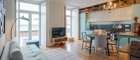 Una sala de estar moderna con sofá, televisión y comedor con sillas y una mesa.