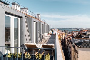 Terraço no telhado com assentos, corrimão e vista para a cidade.