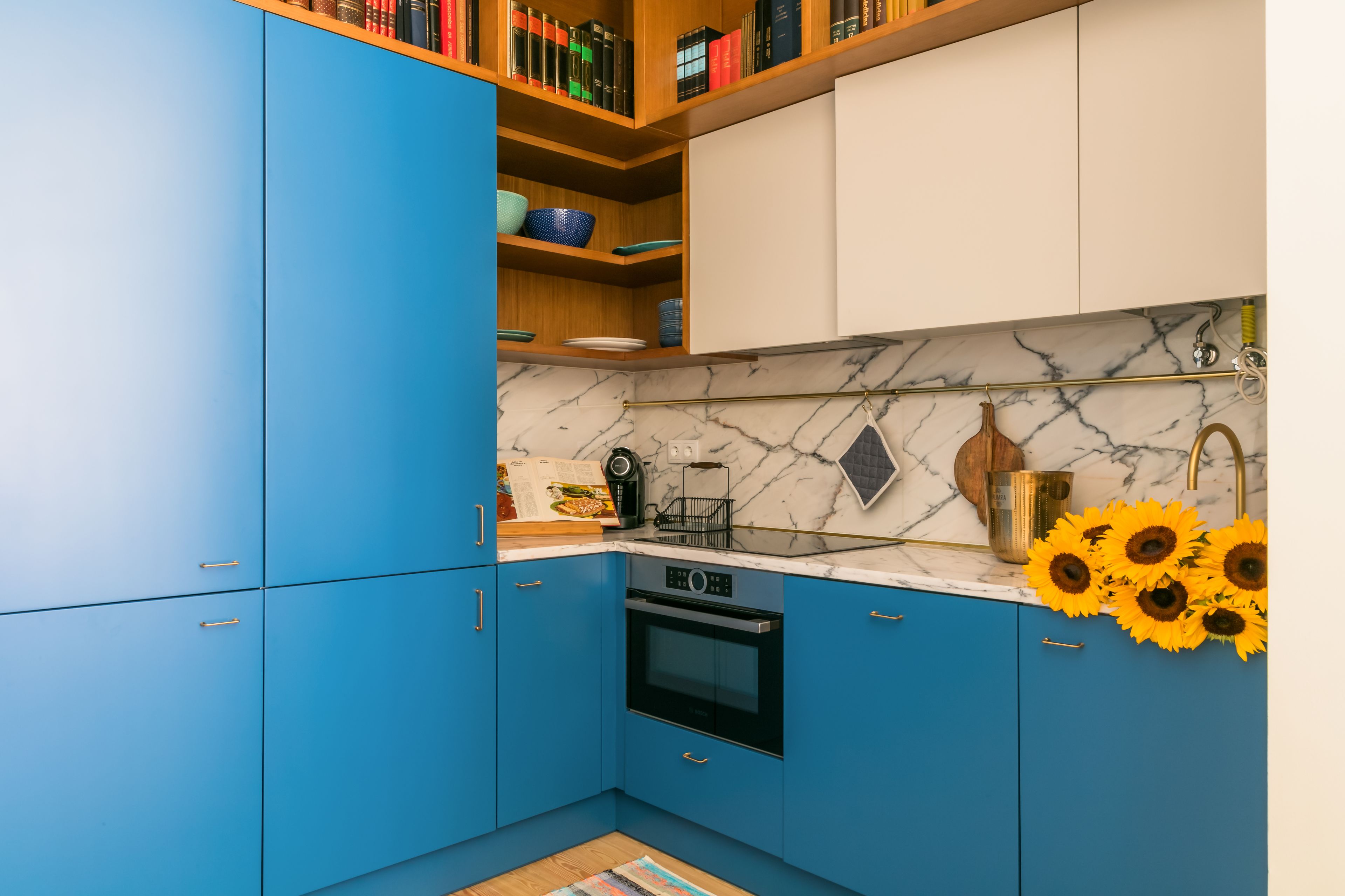 A kitchen with blue cabinets, a marble countertop, and a built-in oven.