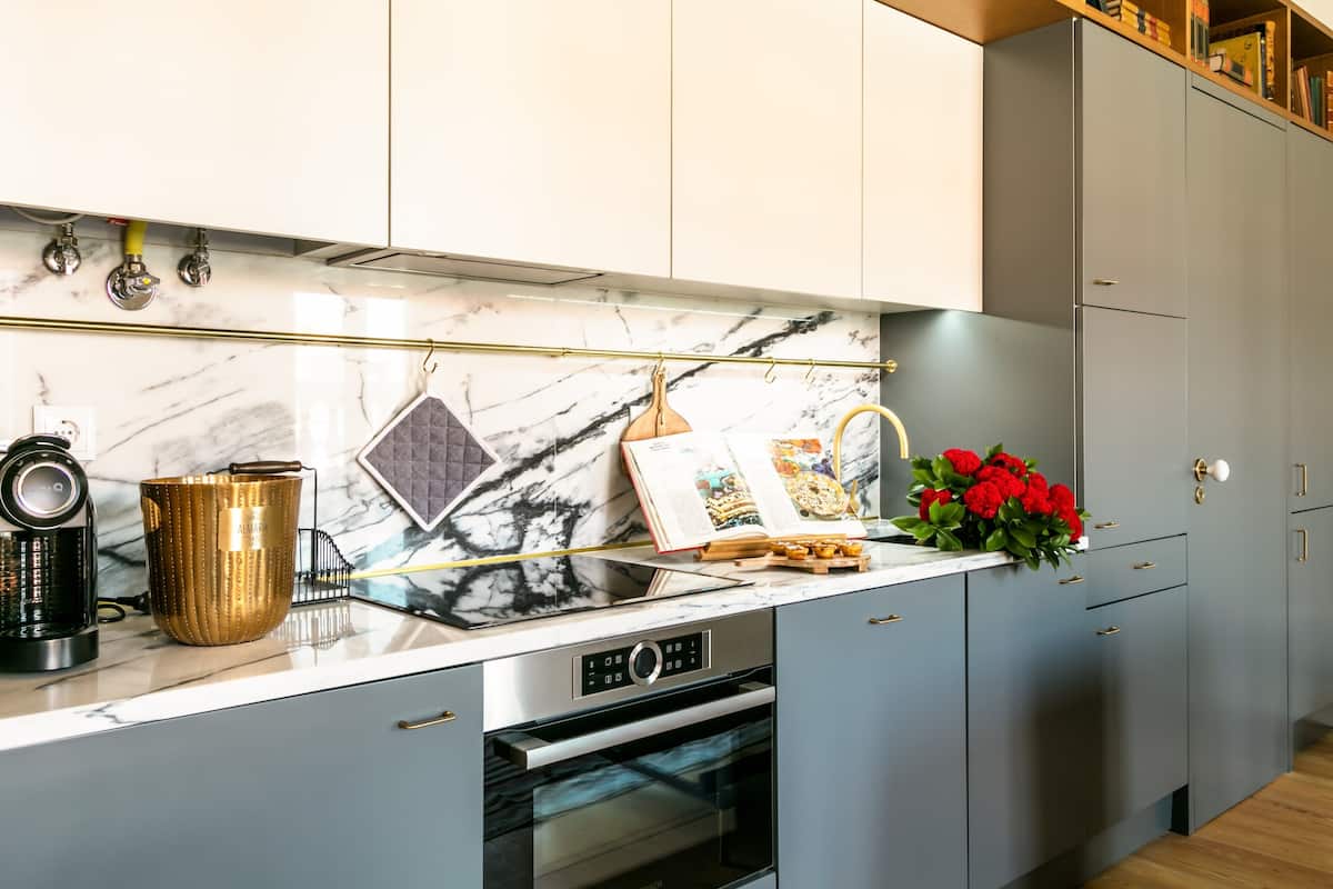 Una cocina moderna con armarios grises, salpicadero de mármol y horno Bosch.