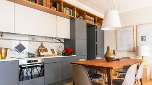 Una cocina moderna con gabinetes grises, una mesa de comedor de madera y un horno empotrado.