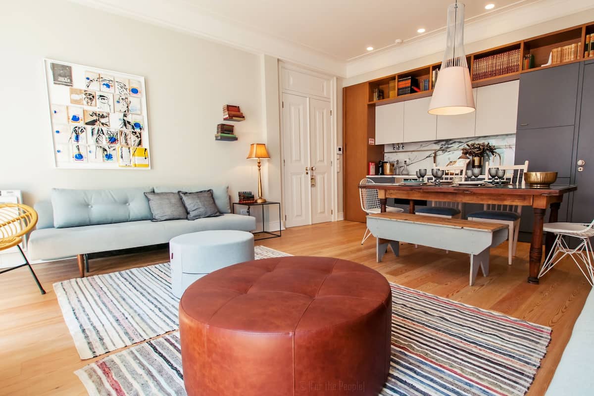 Una sala de estar moderna con sofá, reposapiés y comedor con banco y sillas.