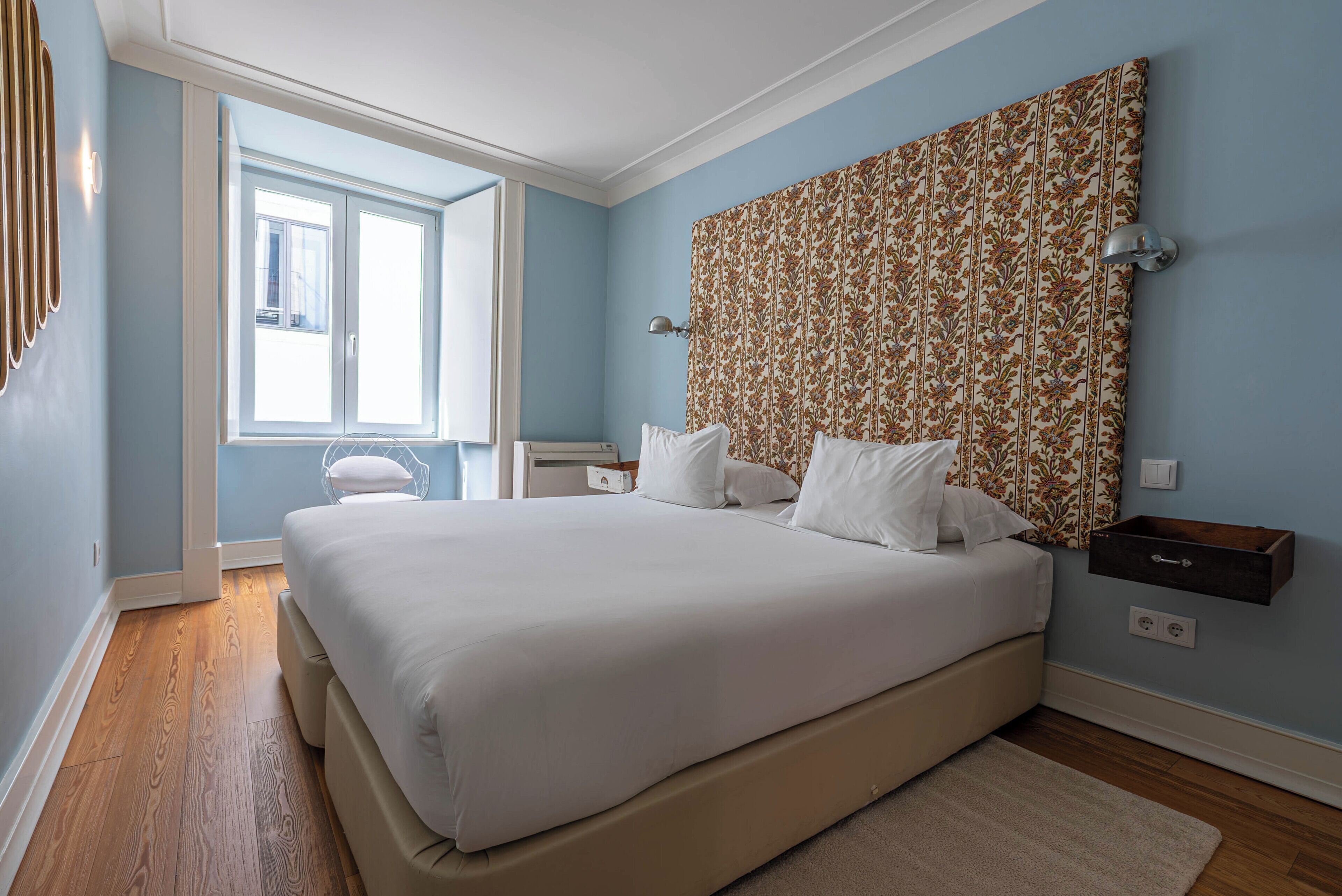 A bedroom with a large bed, a window, and a patterned headboard.