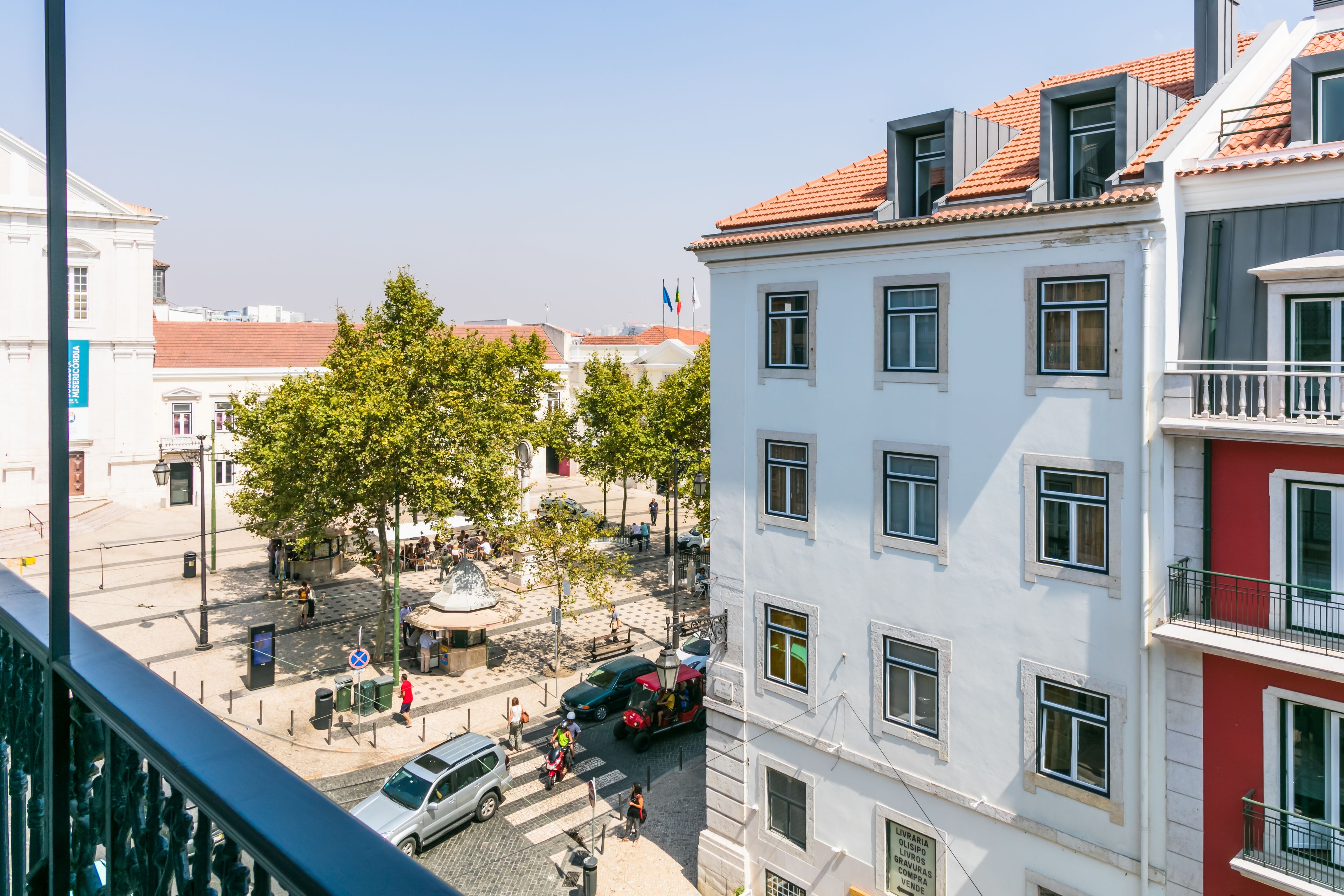 A multi-story building with a white facade and red roof tiles.