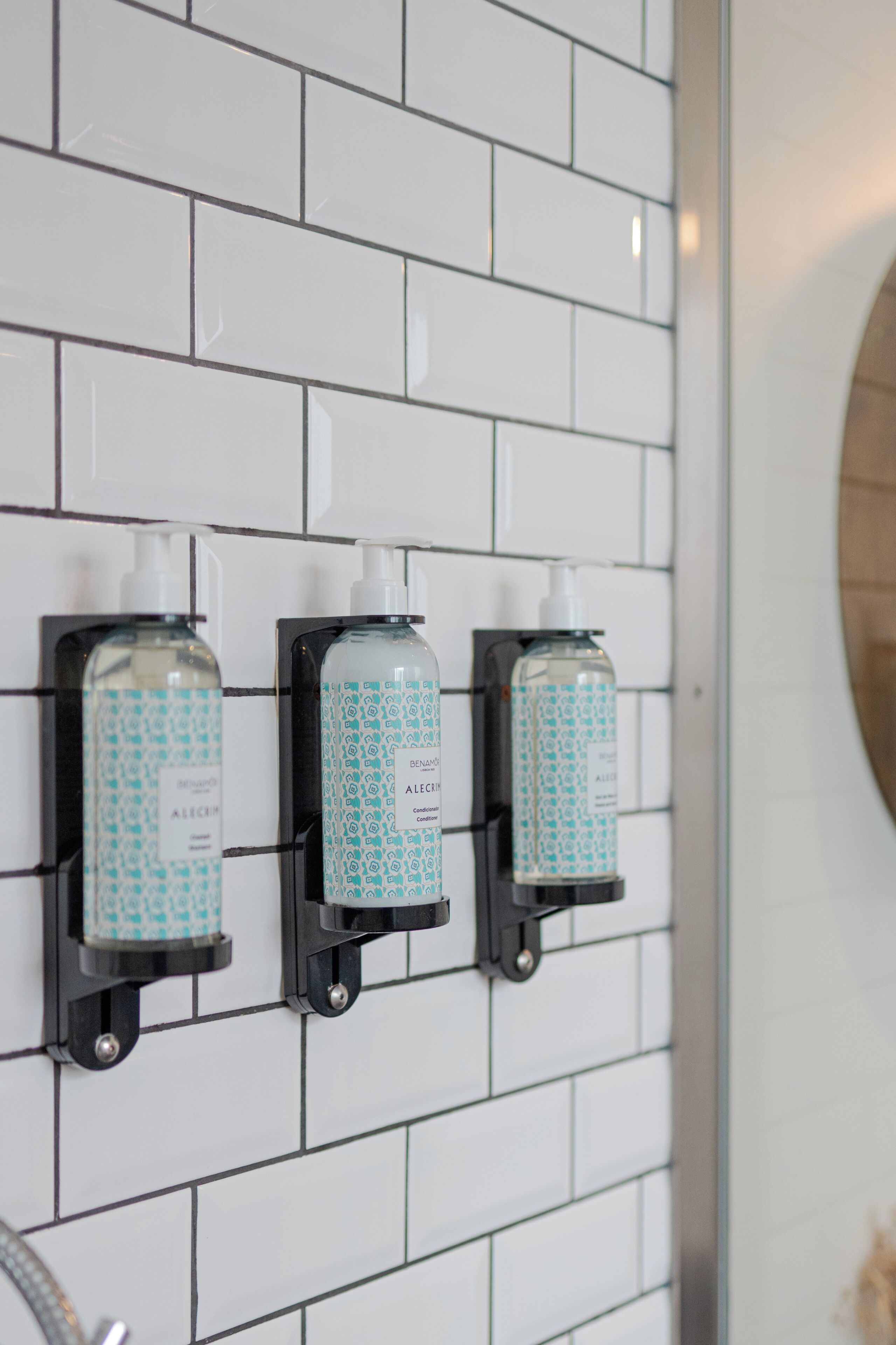A bathroom with three hand sanitizer dispensers mounted on a tiled wall.
