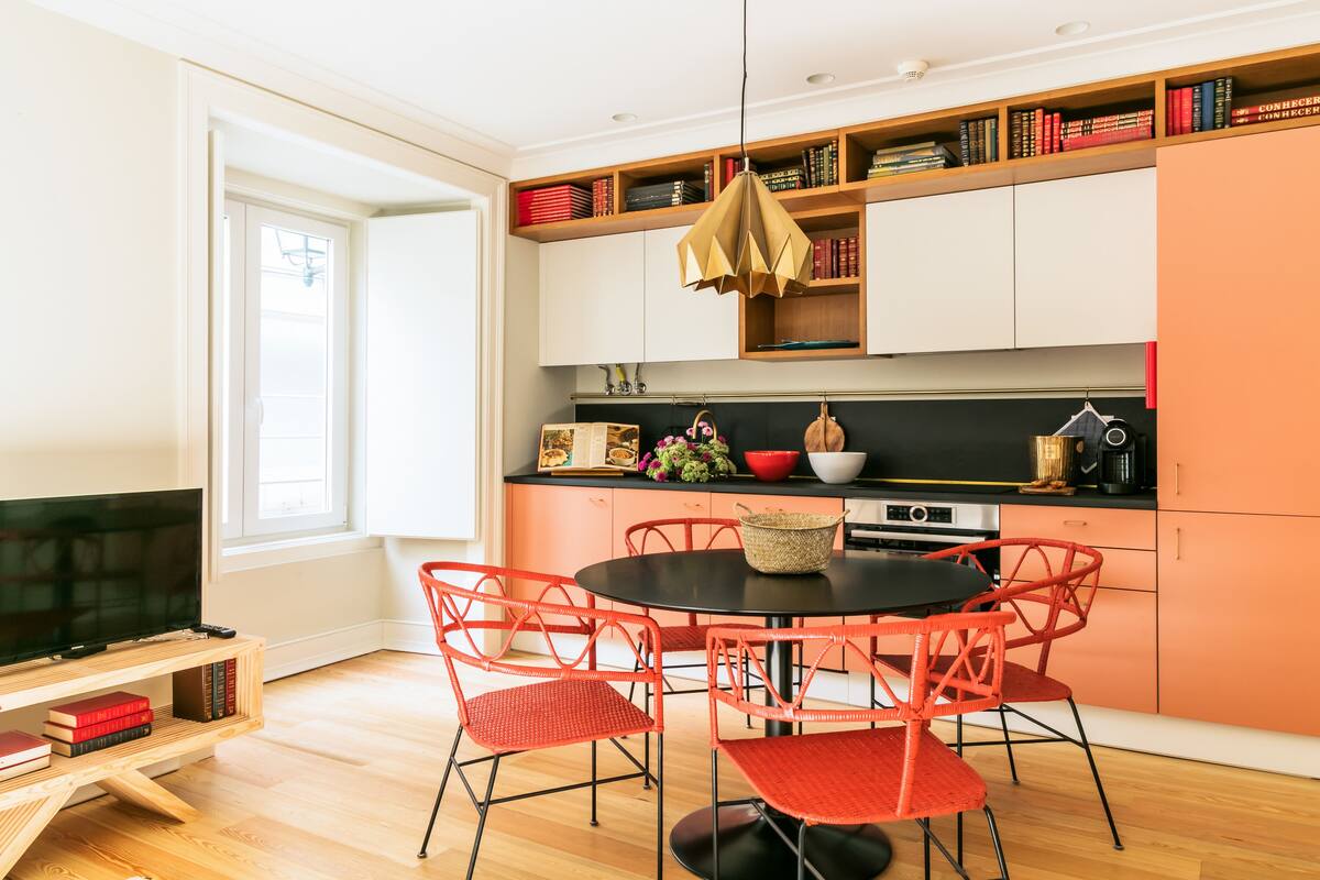 Una cocina moderna con comedor, estanterías de madera con libros y un televisor.