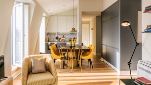 Una sala de estar moderna con un sofá, una mesa de comedor con sillas, un televisor y una lámpara.