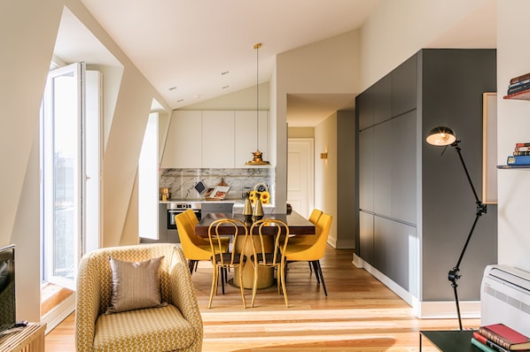 Una sala de estar moderna con un sofá, una mesa de comedor con sillas, un televisor y una lámpara.