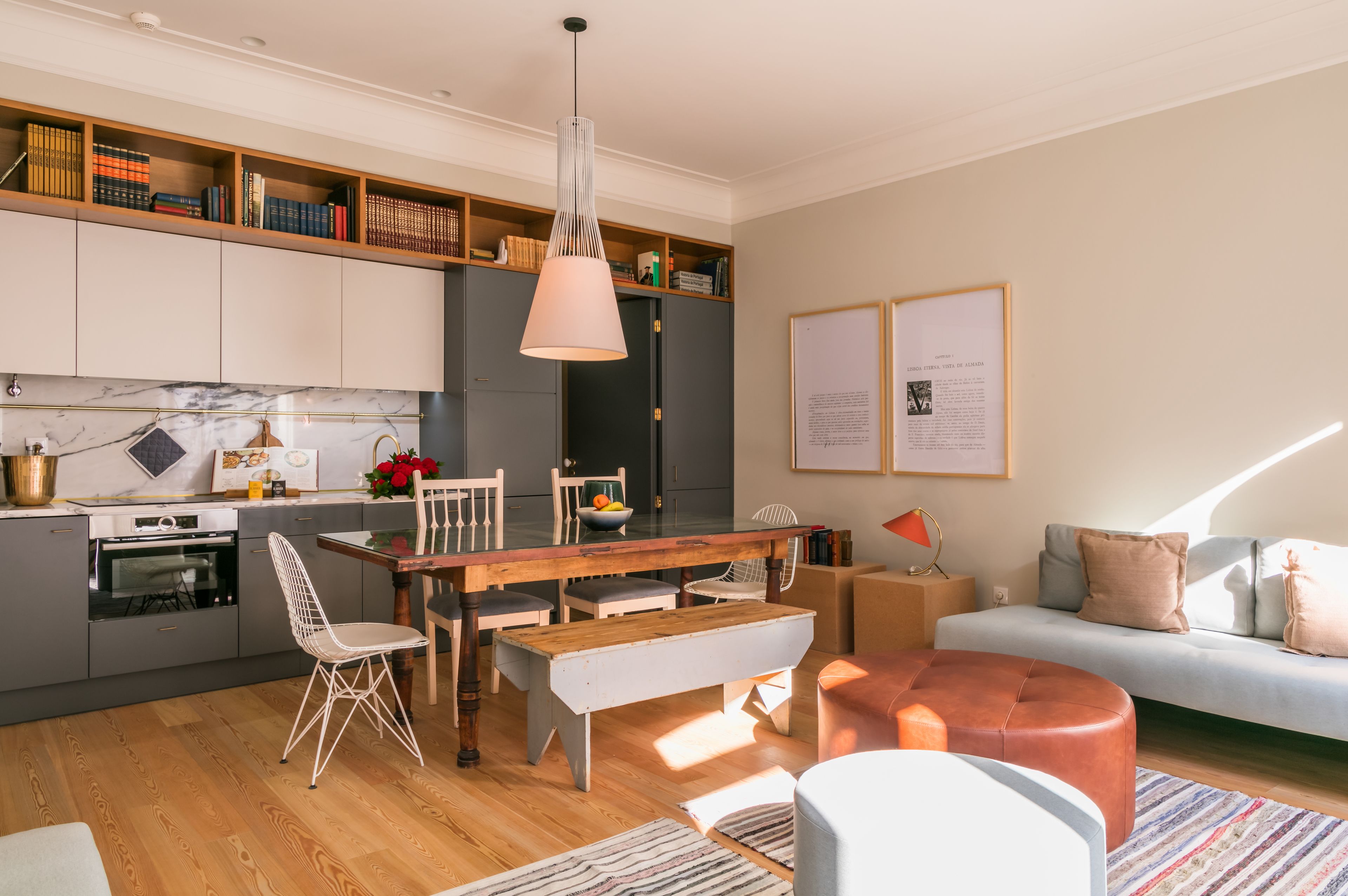 A modern kitchen with grey cabinets, a wooden dining table, and a pendant light.