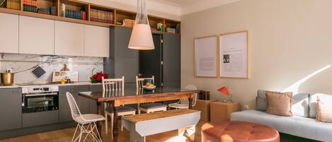 A modern kitchen with grey cabinets, a wooden dining table, and a pendant light.