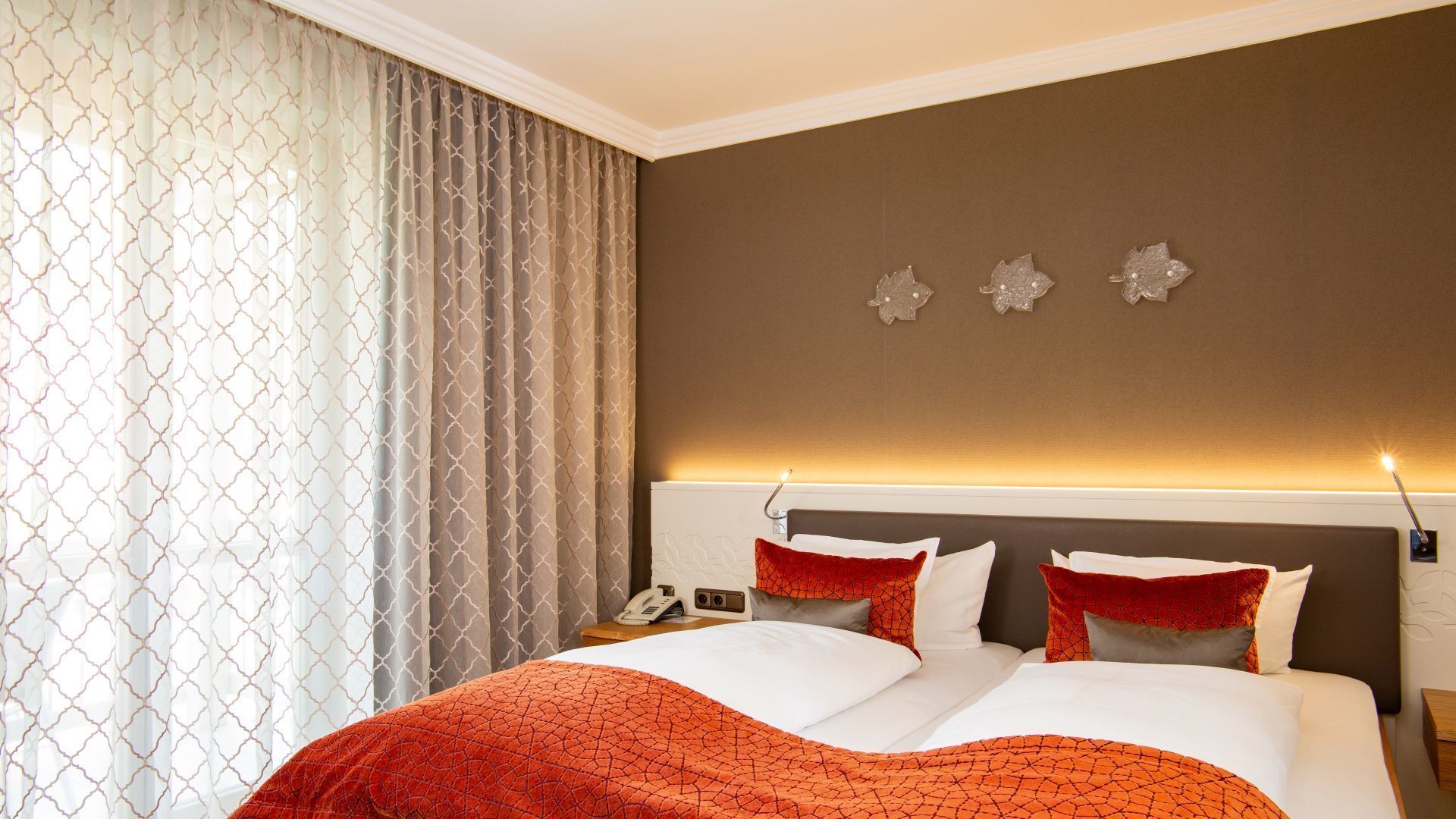 Een hotelkamer met een groot bed, een nachtkastje met een lamp en een aan de muur bevestigd telefoontoestel.