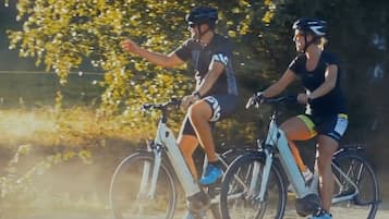 Dos ciclistas en un sendero de tierra con árboles al fondo.
