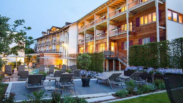 A multi-story hotel with outdoor seating and a garden area. - Hotel St Florian (Frauenau)